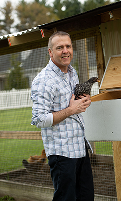 Cauley holding a chicken in front of the chicken coop