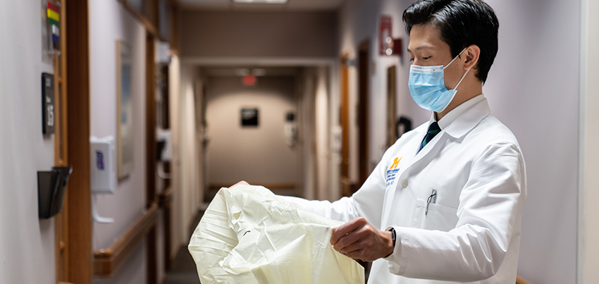 Asian male doctor putting on protective equipment