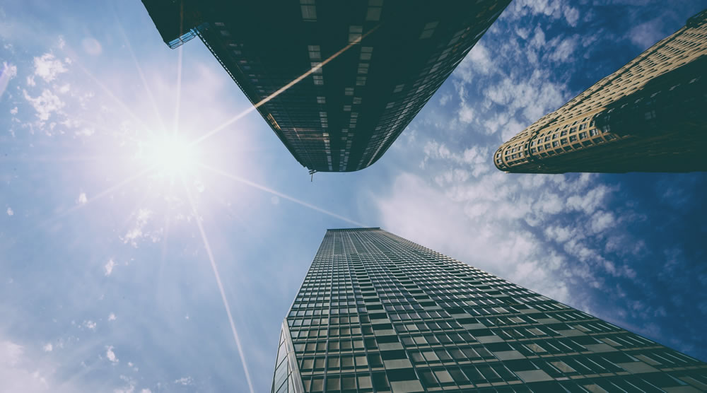 looking up at the sun shining between two high rise buildings