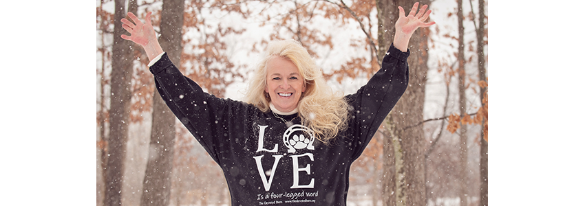 Ellen Hoff stands outside with her arms overhead in joy