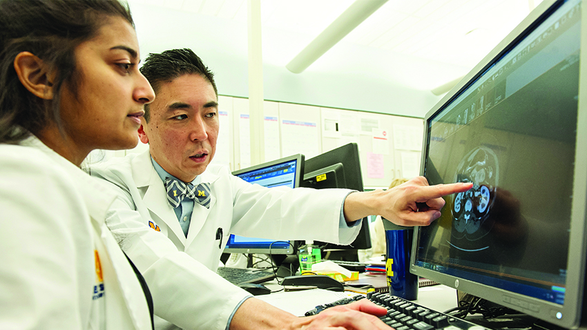 Clifford Cho, M.D. with student looking at a scan of a pancreas