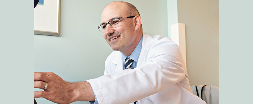 image of John Magenau, M.D. reaching across a desk