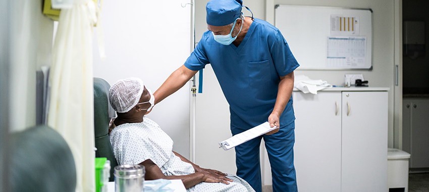 image of doctor in a mask talking to Black female patient also wearing a mask