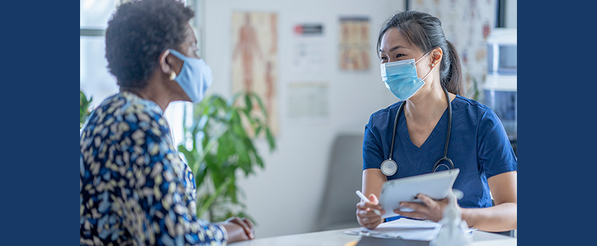 image of older, Black woman talking to female Asian healthcare worker