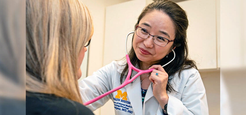 An Asian-American female doctor listens to her patient's heartbeat with a stethoscope