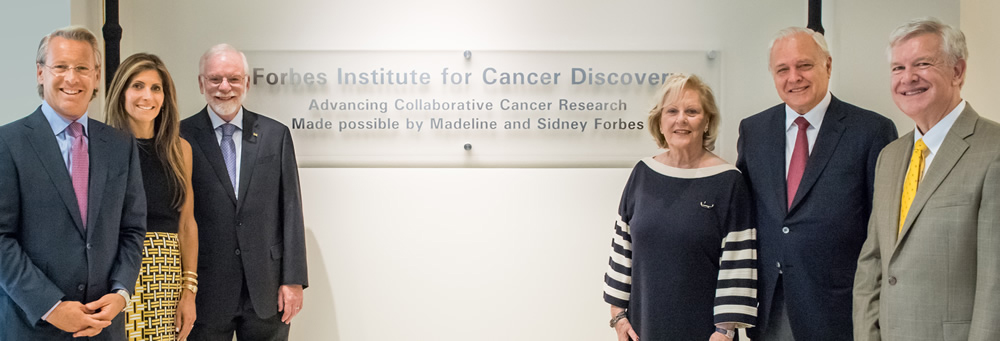 the Forbes family, along with Max Wicha, pose in front of the Forbes Institute for Cancer Discovery sign