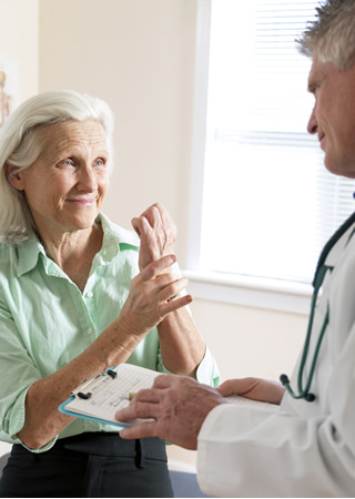 image of woman rubbing her wrist while talking to her doctor