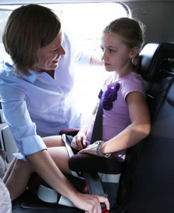 mother fastening child into carseat
