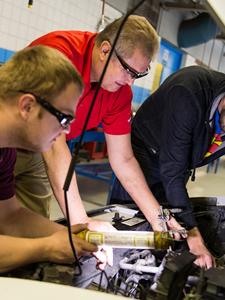 Stan Urban and others work on a car's engine