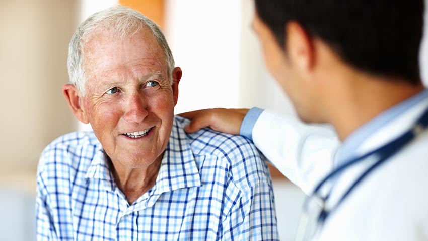 Older man talks with a younger doctor who is clearly listening carefully to him