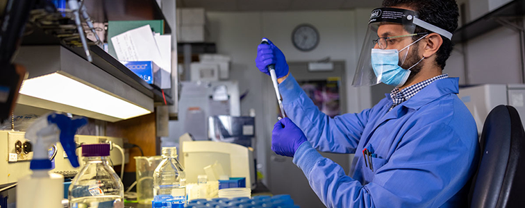 male researcher uses a pipette in a lab