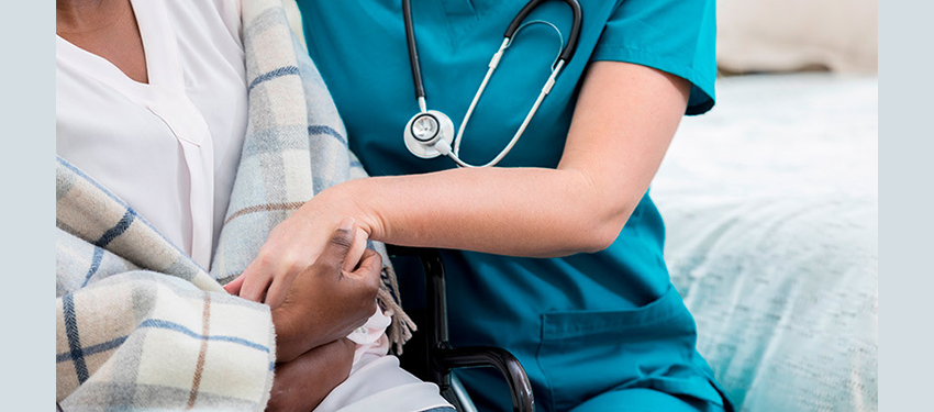 white nurse in scrubs holds the hands of Black patient