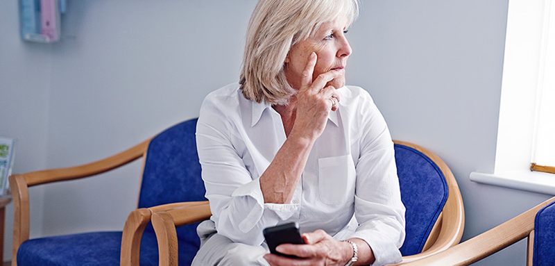 Mature female holding a cell phone looking throughtful