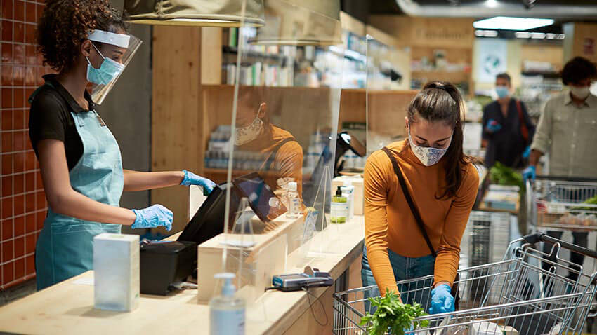 cashier and customer wearing masks at grocery store