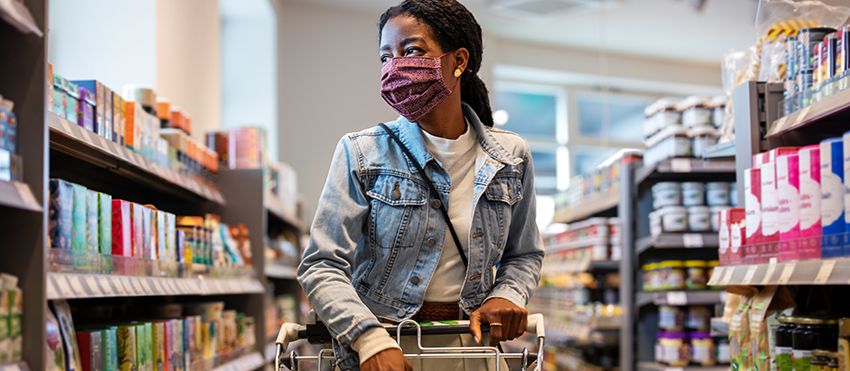 Black woman wearing a mask shops at a grocery store