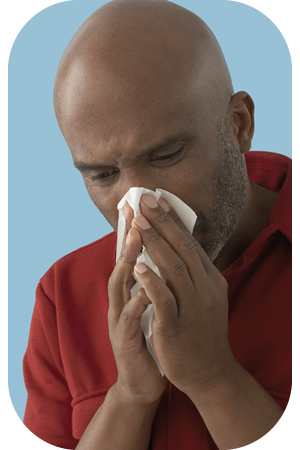 Image of man sneezing or coughing into a tissue