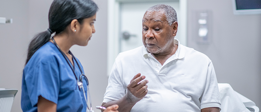 Mature Black man talks to nurse in an exam room