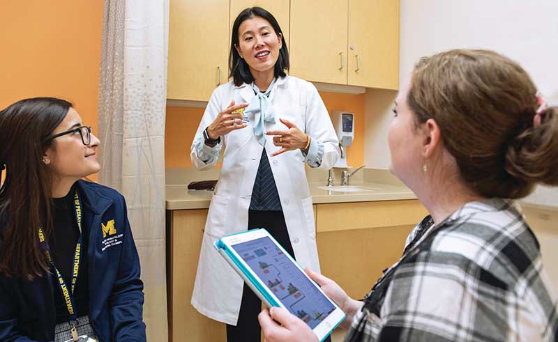 Sung Won Choi, M.D. explains her app to a patient and nurse