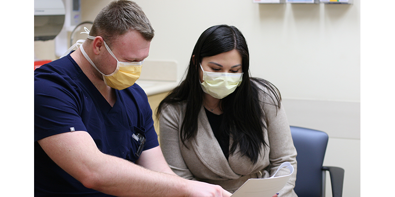 Male nurse sits with female patients looking over paperwork