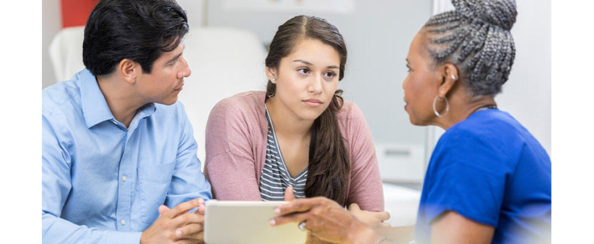 A young couple consult with a Black healthcare provider