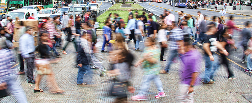 blurry photo of a large group of people crossing the street in a city