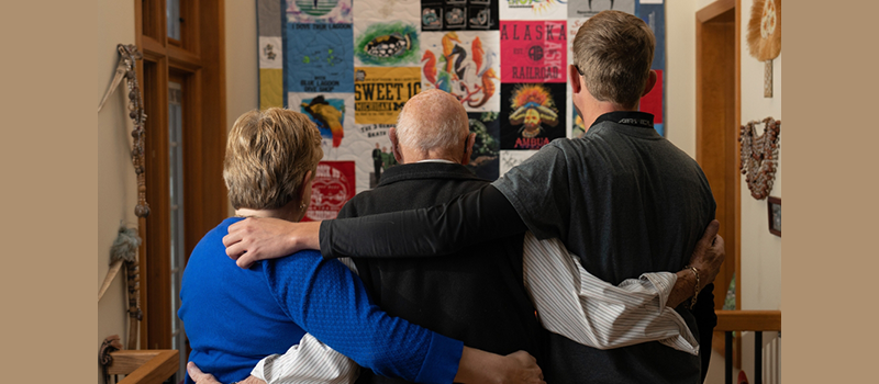 The backs of three people looking at a wall of memorabilia