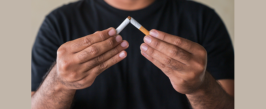 close up a man's arms and hands as he breaks a cigarette in half