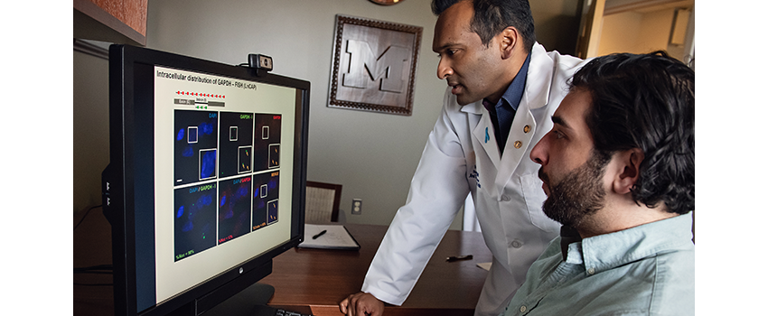 Arul Chinnaiyan, PhD and assistant study images on a computer screen