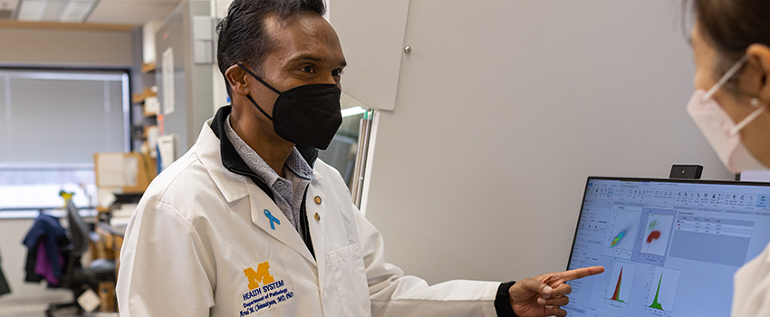 Arul Chinnaiyan, MD, PhD stands in front of a computer screen