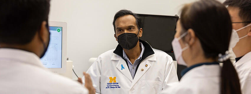 Arul Chinnaiyan, MD, PhD talks to his colleagues while masked