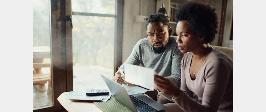 Black couple sit in front of computer reviewing bills