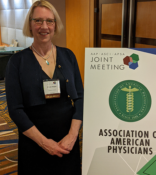 Dr. Diane Harper stands next to the AAP logo