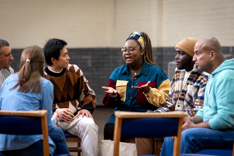 A diverse group of people sit in chairs discussing
