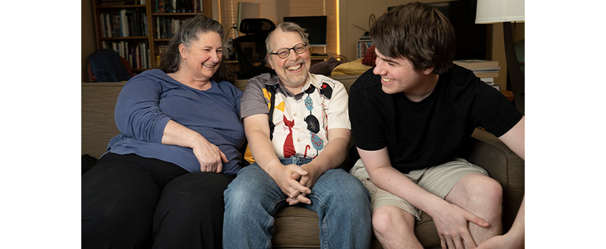 Ward with his wife, Kathleen Folger, and son, Ethan, laughing together on their couch