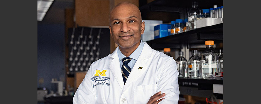 Joshi Alumkal, a dark-skinned, older man standing with a smile in his lab