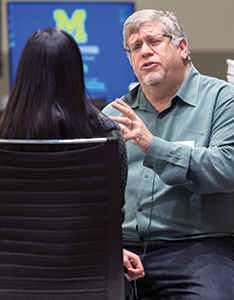 Ken Resnicow, PhD sitting and talking with a woman with long black hair