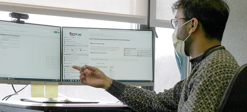 Man sitting in front of computer pointing to something on the screen