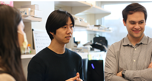 Three students, two Asian-American men and a woman, talking