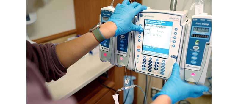 nurse's gloved hands set up a chemotherapy pump