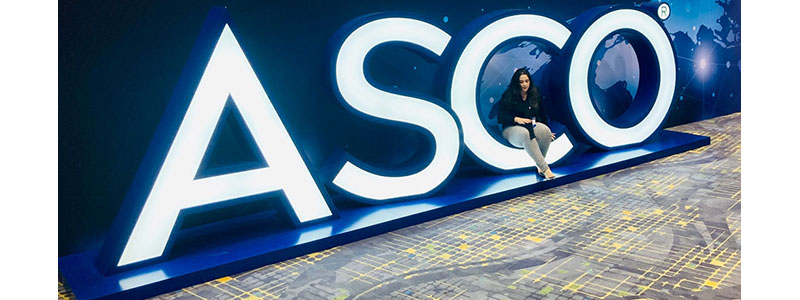 Woman sits on a large blue ASCO sign