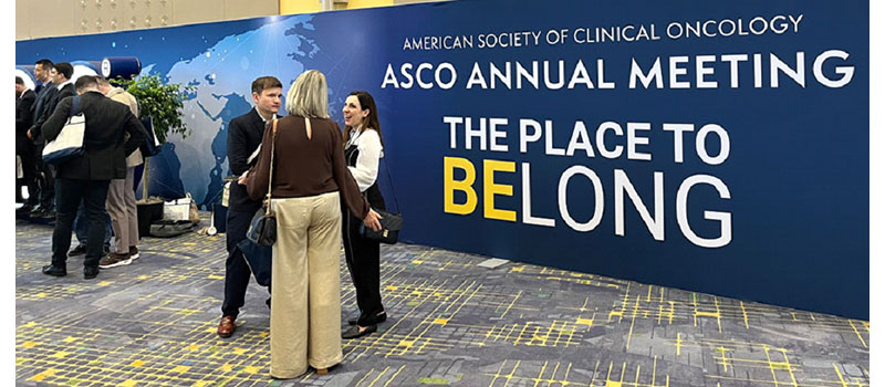 conference attendees stand in front of the ASCO 2025 banner