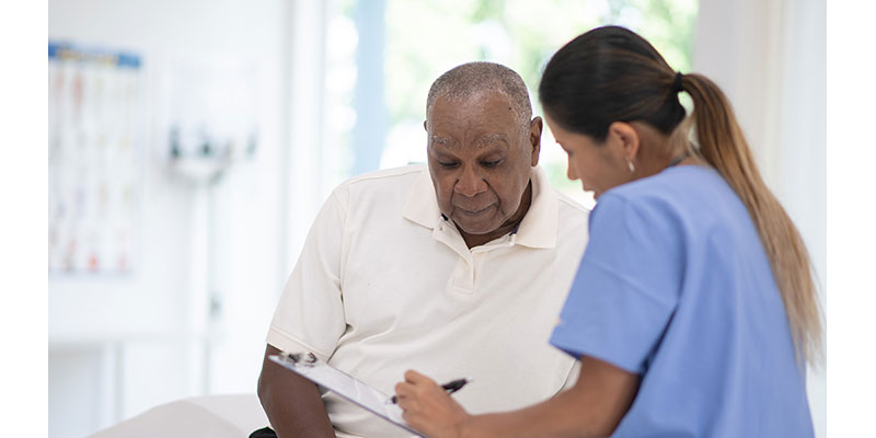 Older Black man with doctor in exam room