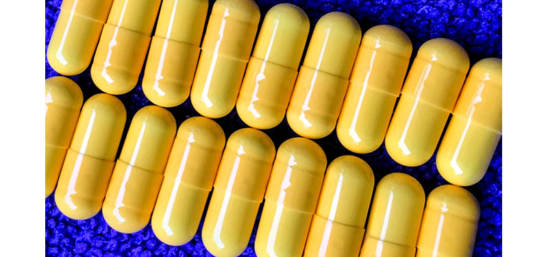Close up of yellow pills arranged in rows on a blue background