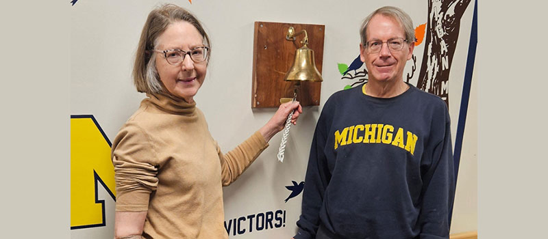 older woman and man stand next to the bell cancer patients ring when treatment is over
