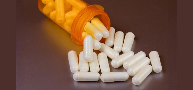white pill spilling out of an orange bottle
