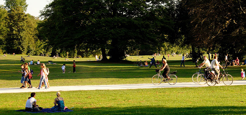 Sunny day at the park with people walking and riding bikes