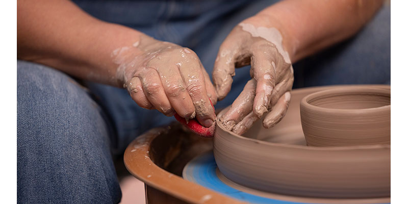close up of Judith Hoge's hands shaping the clay on the pottery wheel