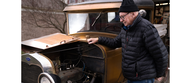 Older man standing near the front of Model T-like car