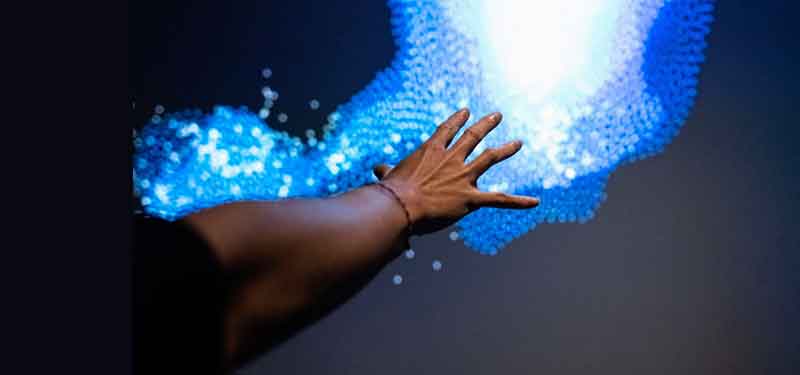 Image of hand reaching out to touch a large, glowing screen of color