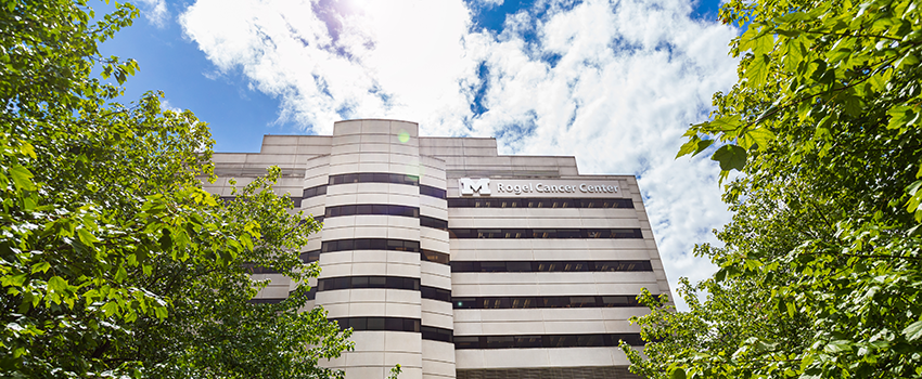 Rogel Cancer Center building between trees with sunshine